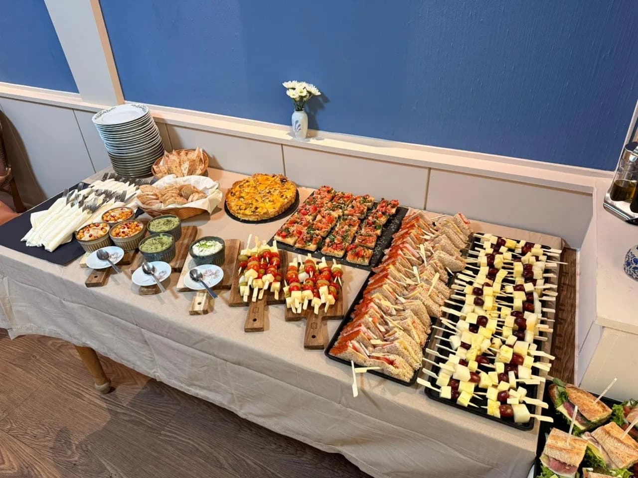Gedecktes Buffet im Raum mit Spießen, Bruschetta, Quiche und Sandwiches
